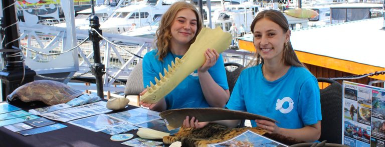 Two education staff smile with artifacts at an Ocean Wise table