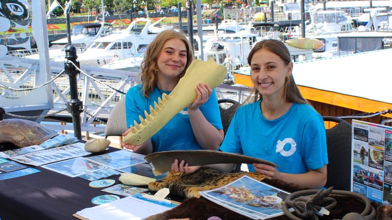 Two education staff smile with artifacts at an Ocean Wise table